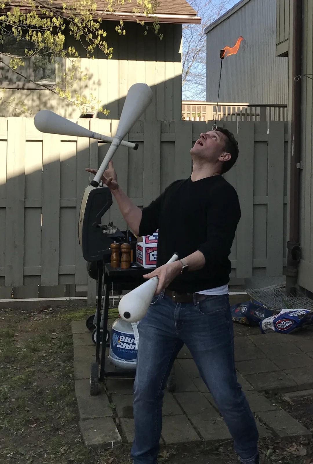 Jacob Abernethy juggling white clubs in a backyard