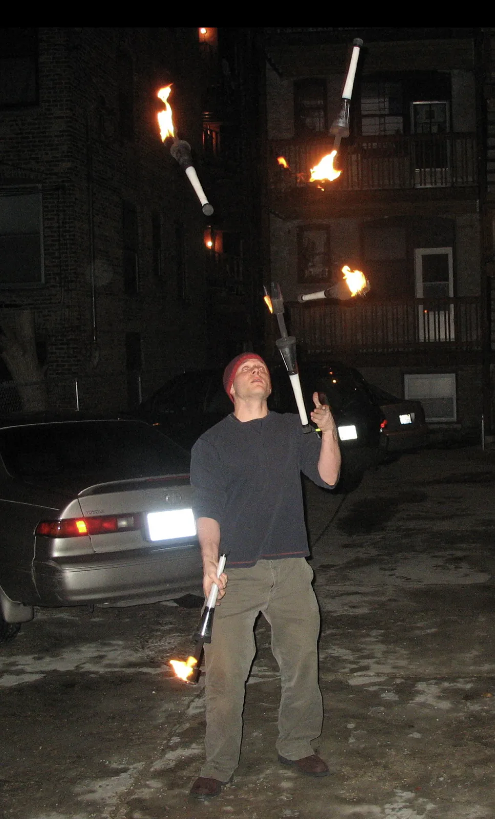 Jacob Abernethy juggling three flaming clubs outdoors at night