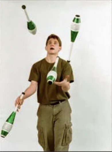 Jacob Abernethy juggling green clubs indoors