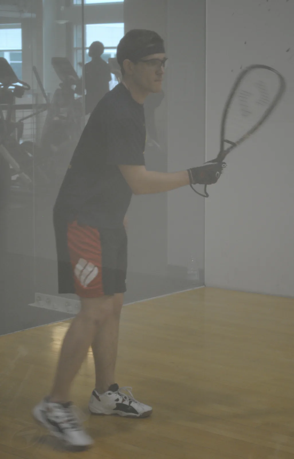 Jacob Abernethy holding a racquetball racquet on an indoor glass-walled court